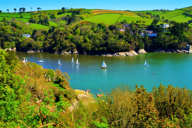 Yachts sailing Devon coast calm blue sea Dart estuary near Dartmouth in beautiful weather with colourful countryside Yachts sailing Devon coast calm blue sea Dart estuary near Dartmouth in beautiful weather with colourful countryside devon stock pictures, royalty-free photos & images