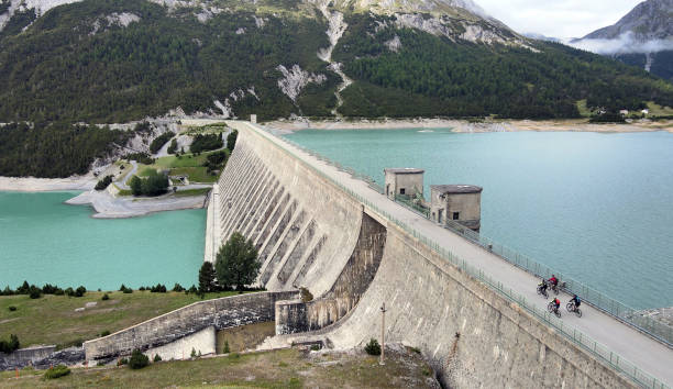 istock Cyclists crossing an alpine lake dam in Italy 1351908208