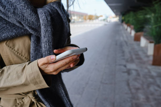 istock Woman is holding a modern smartphone, sending a text message or using an app on her mobile phone. Internet technology user. Smartphone close-up. Focus on the phone screen 1351910760