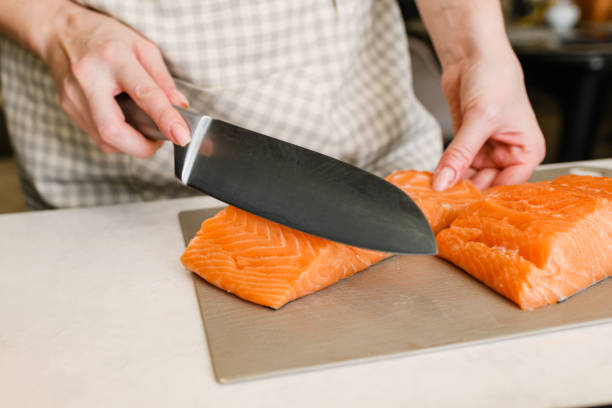 istock Female hands cutting fillet of red fish 1351912424