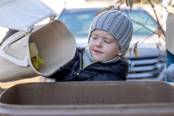 istock Little Boy Composting at Home and Emptying Food Waste in Composting Bin 1351913833