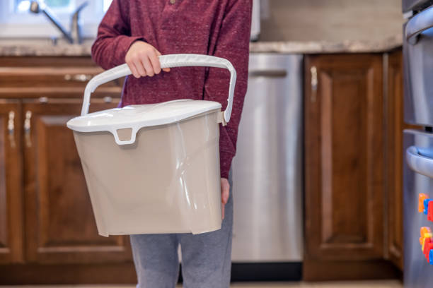 istock Little Boy Composting at Home and Bringing Food Waste to Composting Bin 1351914543