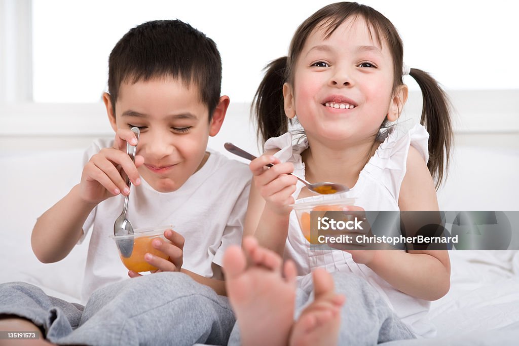 Kids eating fruits cup in bed Siblings age 4 &amp; 5 eating fruits cup in bed 2-3 Years Stock Photo