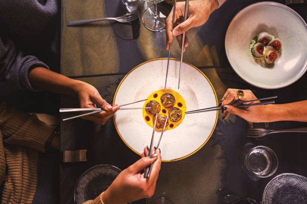 istock Oriental dish based on scallops - table top close-up view with hands taking a portion of food with Chinese chopsticks 1351917248