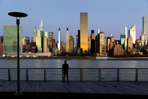 New York Sunrise One person looking at the view of midtown Manhattan skyscrapers during sunrise in New York City. queens new york city stock pictures, royalty-free photos & images