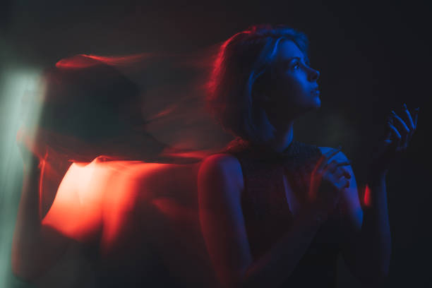 Dual personality. Bipolar mind. Mood disorder. Mental health. Split identity. Woman with depressed peaceful emotion in bright red blue neon light color isolated on dark background.