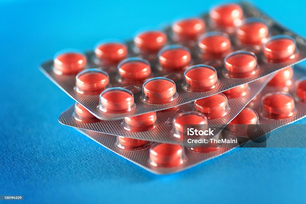 Pink vitamins Pink tablets in plastic clear package on blue background Blue Stock Photo