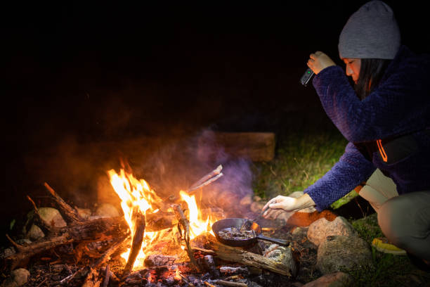 istock Female camper cooking over open campfire 1351943761