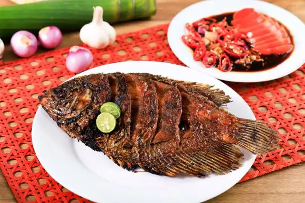 Grilled Gourami  (Ikan Bakar) or Gurame Bakar with Honey and Soy Sauce, Tomato and Chilli in the Background.