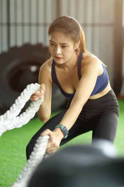istock Female in sport club exercising on battle ropes program 1351951908