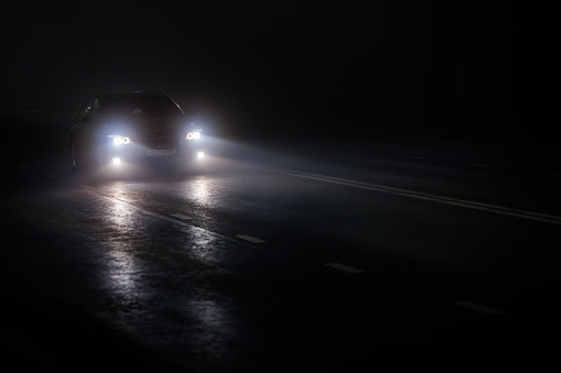 alone sports BMW car moving on empty night foggy road.