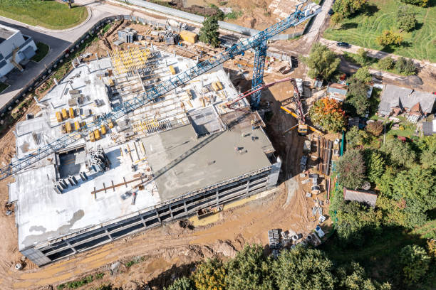 istock builders pouring wet concrete, using hose from concrete pumping machine into floor slab form. aerial view of construction site. 1351960818