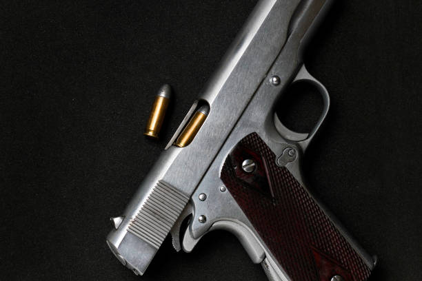 istock Automatic white gun stainless steel pistol weapon model m1911 with real bullet ammo head in black background 1351966106