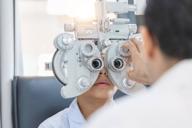 ragazzo che fa esame di controllo oculistico con optometrista in negozio di ottica, optometrista che fa test della vista per paziente bambino in clinica - optometrie foto e immagini stock