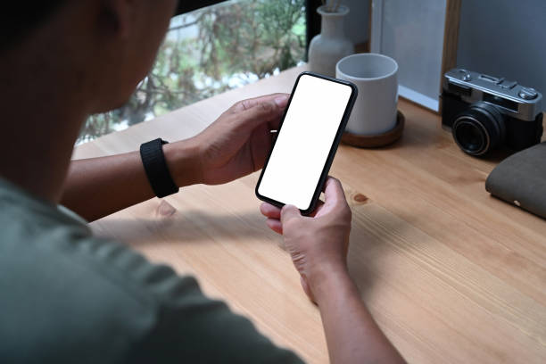 istock Over shoulder view of young man holding smart phone with white screen. 1351967561