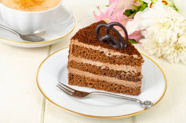 istock Piece of chocolate cake, cappuccino, flowers on table 1351967578