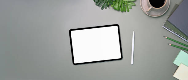 istock Mock up digital tablet, stylus pen, notebook and coffee cup on gray background. 1351967583