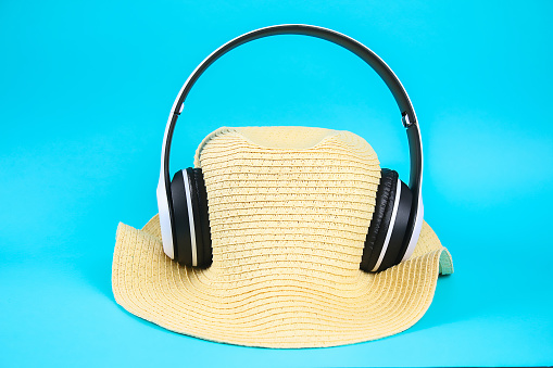 Hat in white wireless headphones on a blue background. The concept of rest, relaxation.