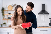 Loving husband surprising charming wife with present gift box on romantic day