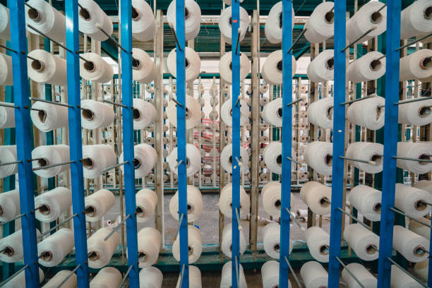 istock White yarn spools bobbin thread cones in a order on industrial warping knitting beaming machine in textile factory 1351977265