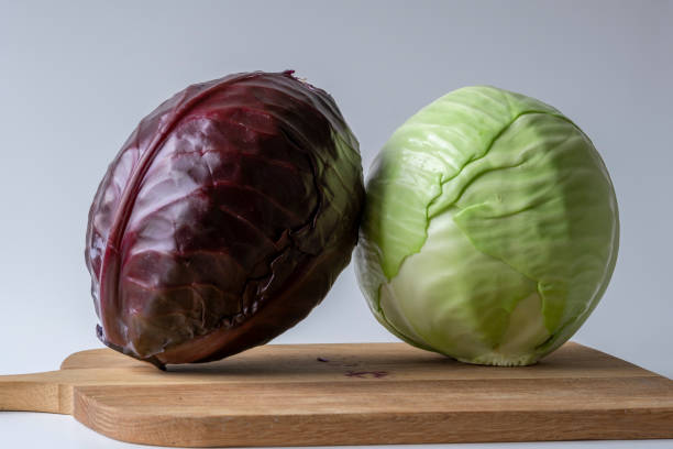 White and red cabbage on wooden chopping board prepare cooking White and red cabbage head on a kitchen board, ready for food preparation white cabbage stock pictures, royalty-free photos & images