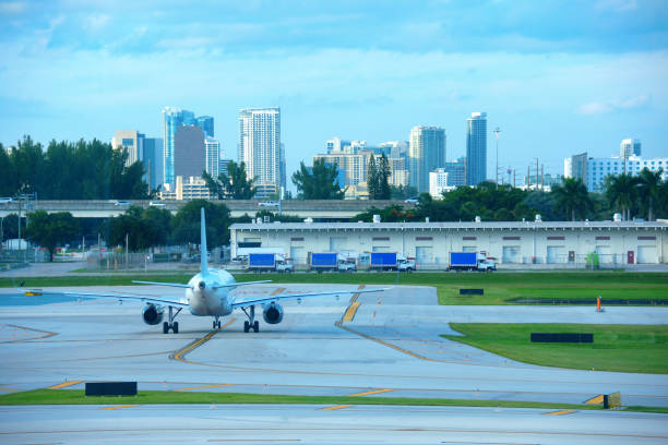 avião de avião a jato comercial na pista do aeroporto internacional com horizonte de fort lauderdale em segundo plano - fort lauderdale florida broward county cityscape - fotografias e filmes do acervo