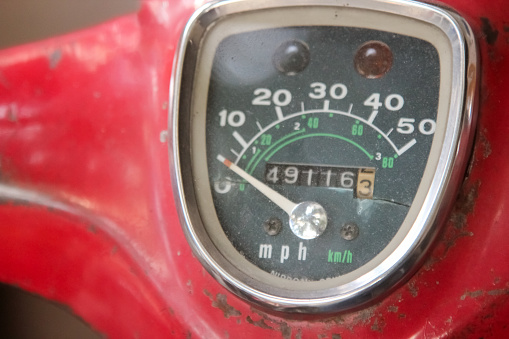 Old motor bike meter close-up shot.Scooter scratched speedometer closeup view.Speedometer dial on a red old scooter or moped