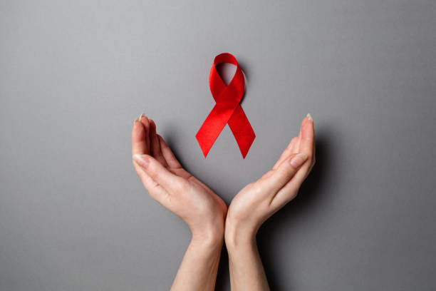 female's hands frame a red ribbon, a symbol of the fight against aids. gray background. flat lay. copy space. the concept of world aids day - world aids day stok fotoğraflar ve resimler
