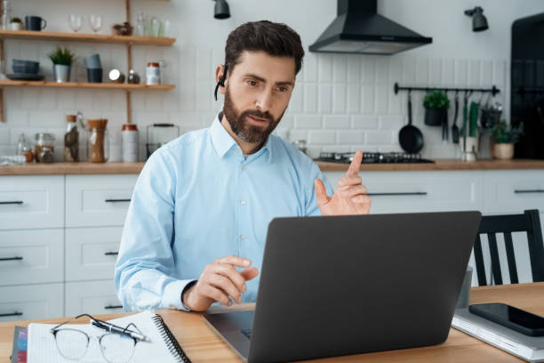 istock Man teacher tutor coach talking to web camera on laptop holding online lesson 1351984546
