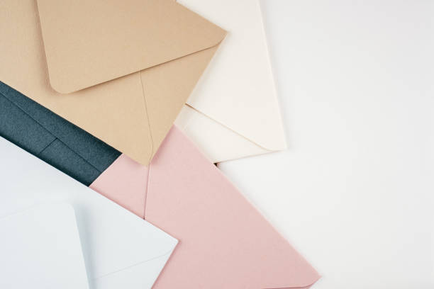 Background image of multi-colored cardboard envelopes lying randomly on white background. Top view, copy space stock photo