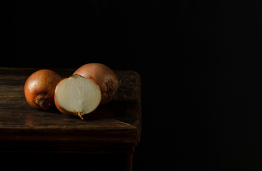 Still life of onions on wooden table against black background
