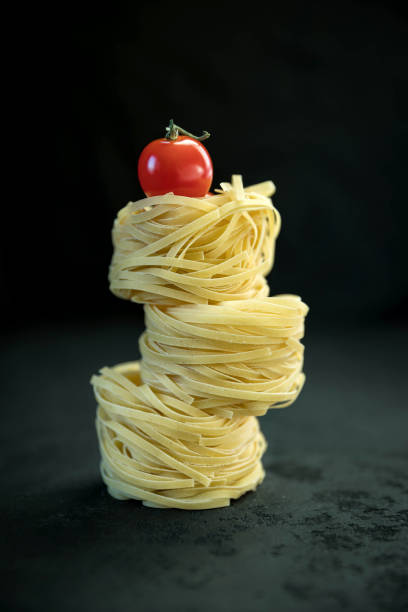 Raw tagliatelle pasta  and tomato .
