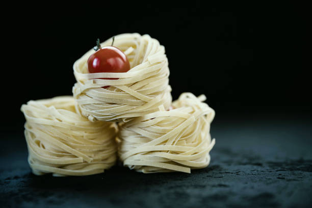 Raw tagliatelle pasta  and tomato .