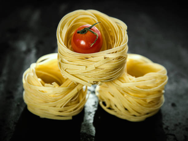 Raw tagliatelle pasta  and tomato .