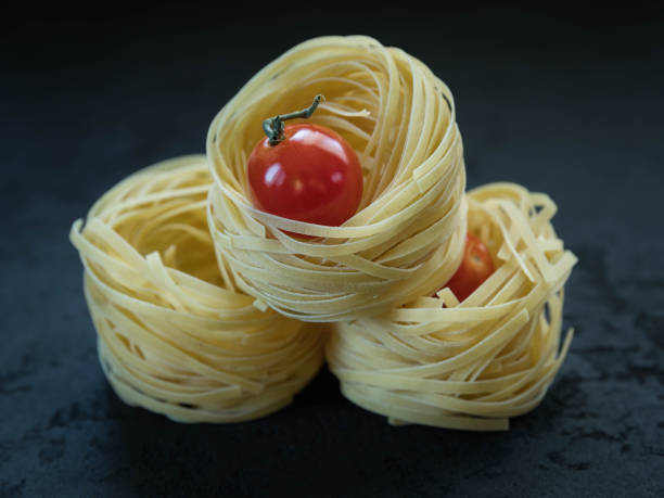 Raw tagliatelle pasta  and tomato .