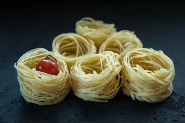 Raw tagliatelle pasta  and tomato .