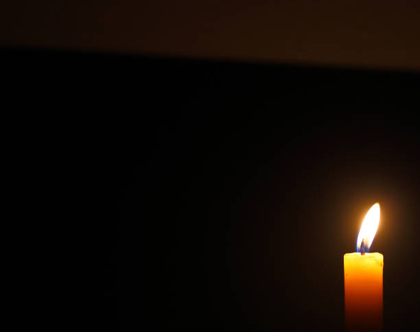 istock Close up single candle light and flame on black background 1351998473