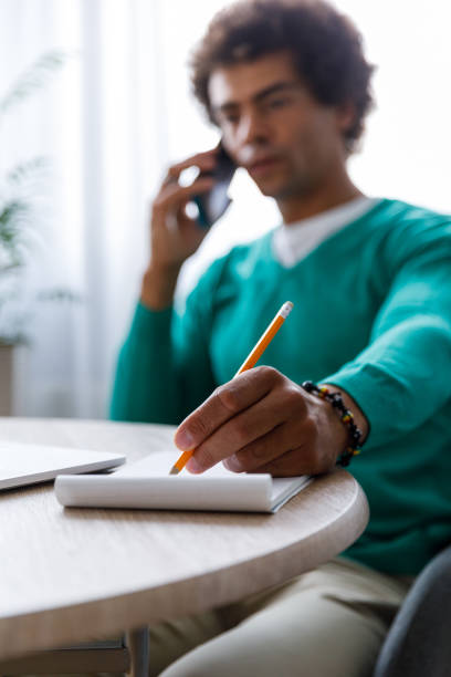 istock Male entrepreneur writing down notes during a conference call 1352000971