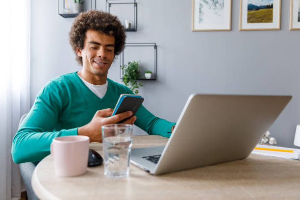 Cheerful man easily managing his home finances through a phone app