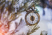 New year and Christmas clock hanging on a snowy fir tree in the forest outdoors