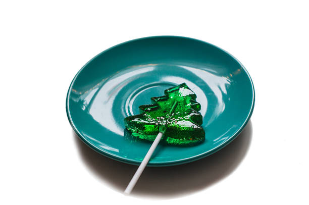 Candy in a shape of fir tree on a plate. Close up, white background.