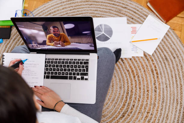 istock Young woman on a video conference call with a professor, highlighting notes 1352005374
