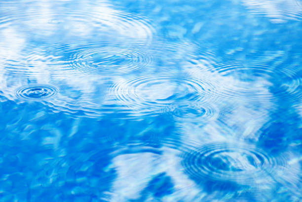 istock Raindrops on pool blue water surface. Blue water texture as background. Stains circles on the water from rain 1352006523