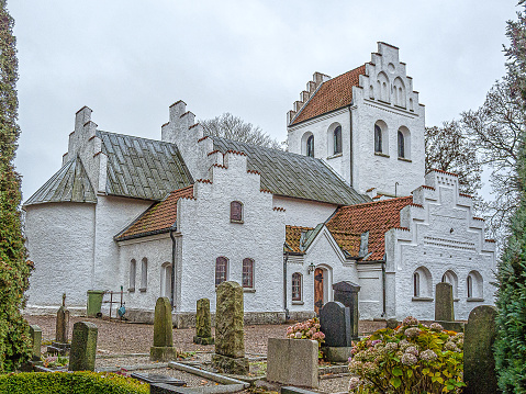 a white ancient country church on a cemetery, Övraby, Sweden, November 6, 2009