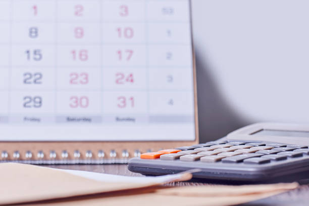 istock Calendar, calculator and stack of coins in office 1352007653