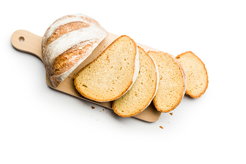 Fresh loaf of bread sliced on cutting board on white background. Top view.