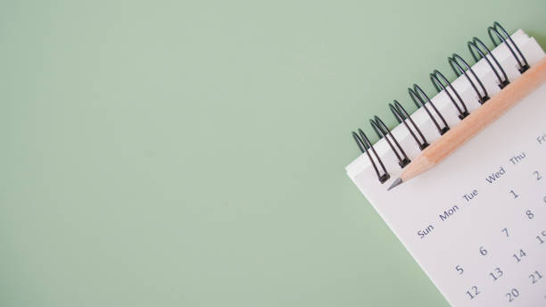 istock sharpen brown pencil on blurred white calendar on green background with copy space for meeting, appointment, timeline, timetable and due date concept 1352009023