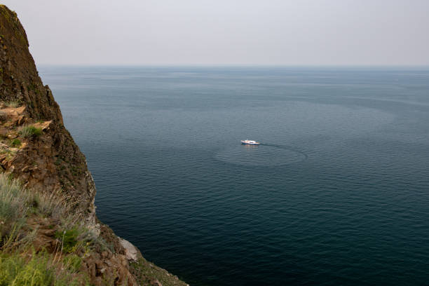 The yacht is turning around on Lake Baikal near the Cape Khoboy. Olkhon Island, Russia.