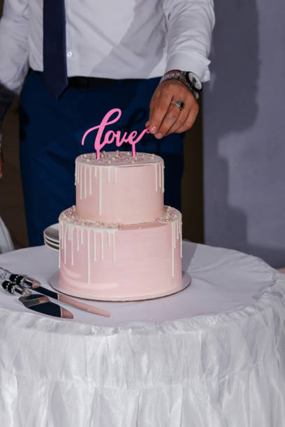 istock The bride and groom cut the wedding pink two-tiered cake. 1352010598
