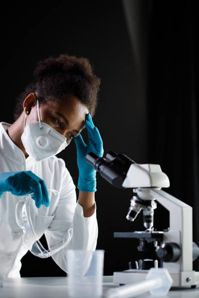 istock Tired female scientist holding her head and taking a break from analyzing samples under a microscope 1352010788